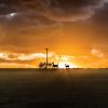 Silhouette of deer against a vibrant sunset with dramatic clouds and power lines