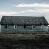 Old green abandoned barn under a vast sky