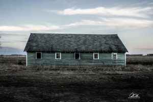 Old green abandoned barn under a vast sky