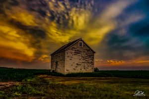 An old wooden barn under a dramatic sunset sky