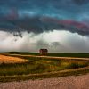 A lone house under dramatic, stormy skies on the plains.