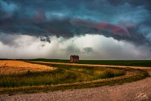 A lone house under dramatic, stormy skies on the plains.