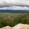 Expansive forest with distant mountains and dramatic clouds overhead
