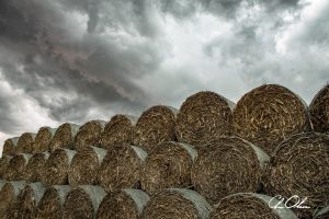 Stacked hay bales beneath dramatic storm clouds